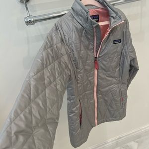 Patagonia, gray quilted jacket with pink zipper and pink liner on the inside.